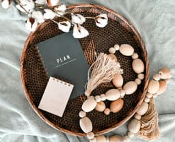 Rond rotan dienblad met houten kralen en een notitieboek